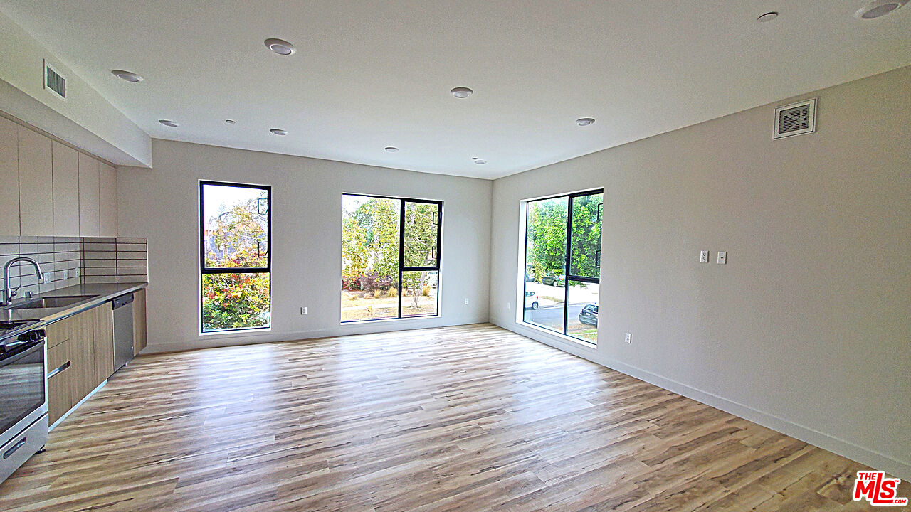 a view of an empty room with window and wooden floor