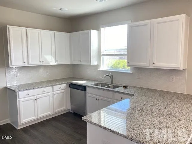 a kitchen with granite countertop white cabinets and window