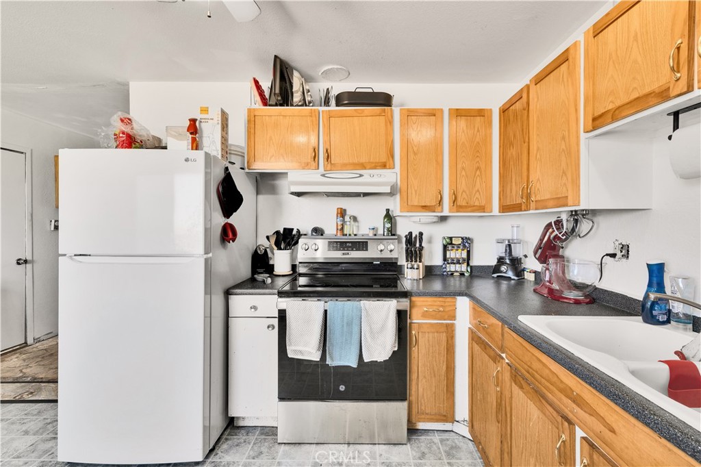 4805 Avenida La Mirada Joshua Tree, CA 92252 - Photo 12 of 38 a kitchen with a refrigerator a sink and cabinets