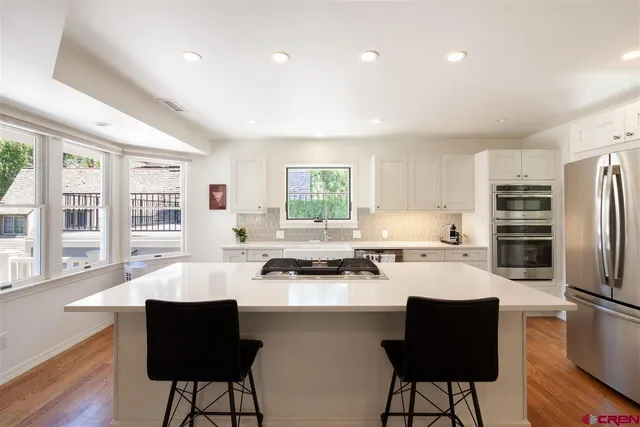 a kitchen with a refrigerator a stove a dining table and chairs with wooden floor