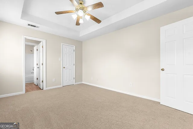 a view of an empty room and chandelier fan