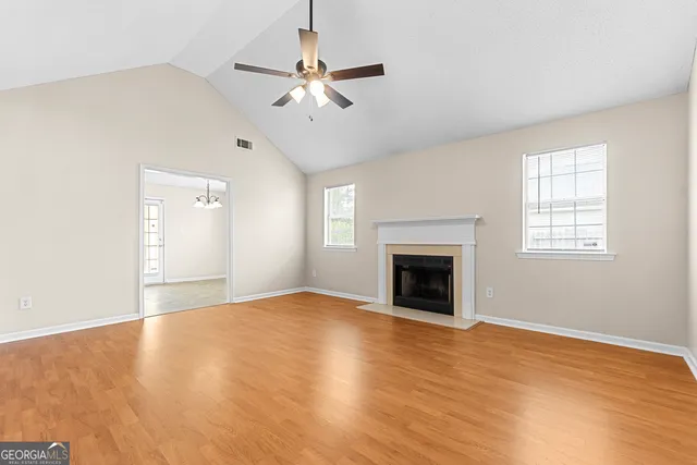 a view of an empty room with a fireplace and wooden floor