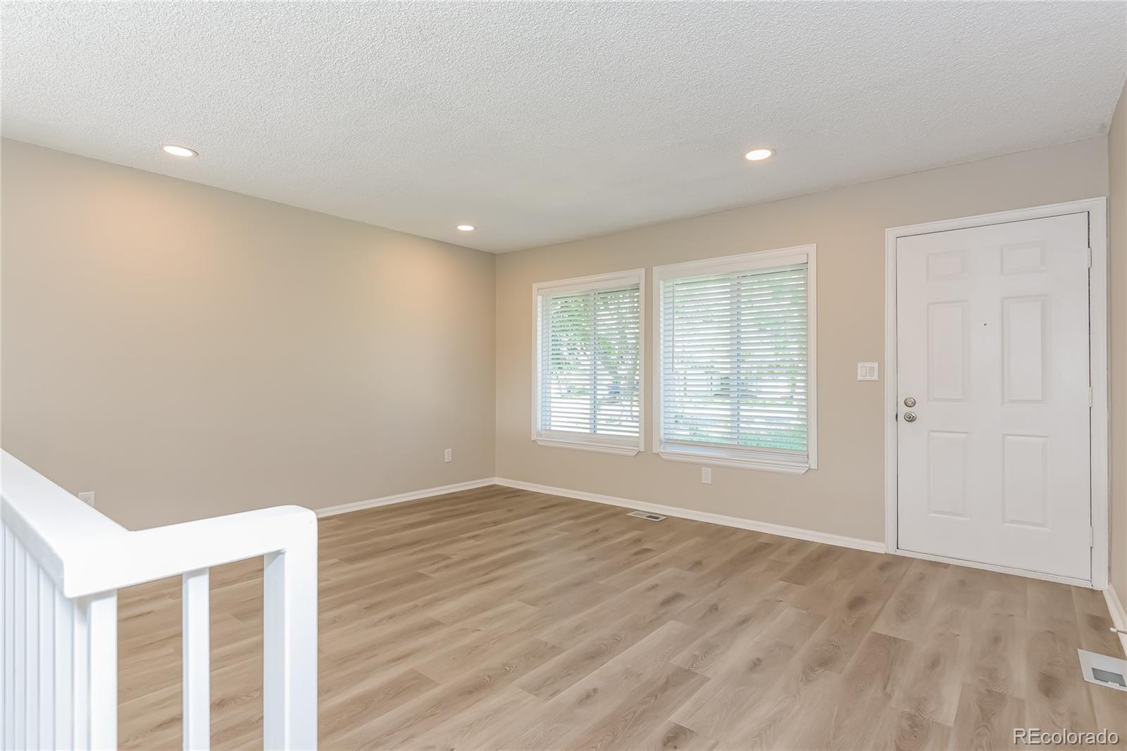 16797 East Mansfield Circle Aurora, CO 80013 - Photo 4 of 17 a view of an empty room with wooden floor and window