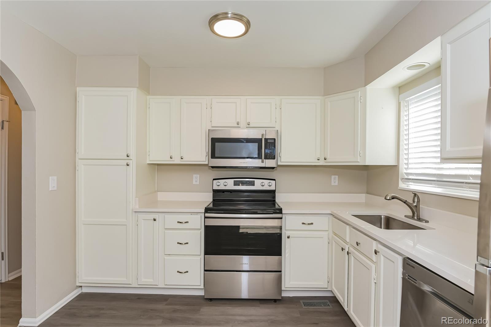 16797 East Mansfield Circle Aurora, CO 80013 - Photo 6 of 17 a kitchen with white cabinets and stainless steel appliances