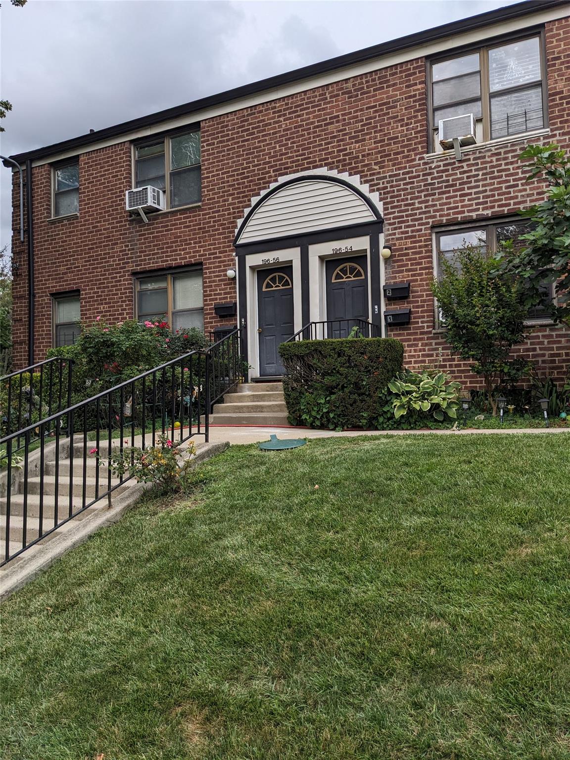 196-54 67th Avenue, Unit 2 Queens, NY 11365 - Photo 1 of 1 View of front facade featuring a front yard, cooling unit, and brick siding