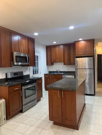 a kitchen with stainless steel appliances granite countertop wooden cabinets a stove a sink and a refrigerator