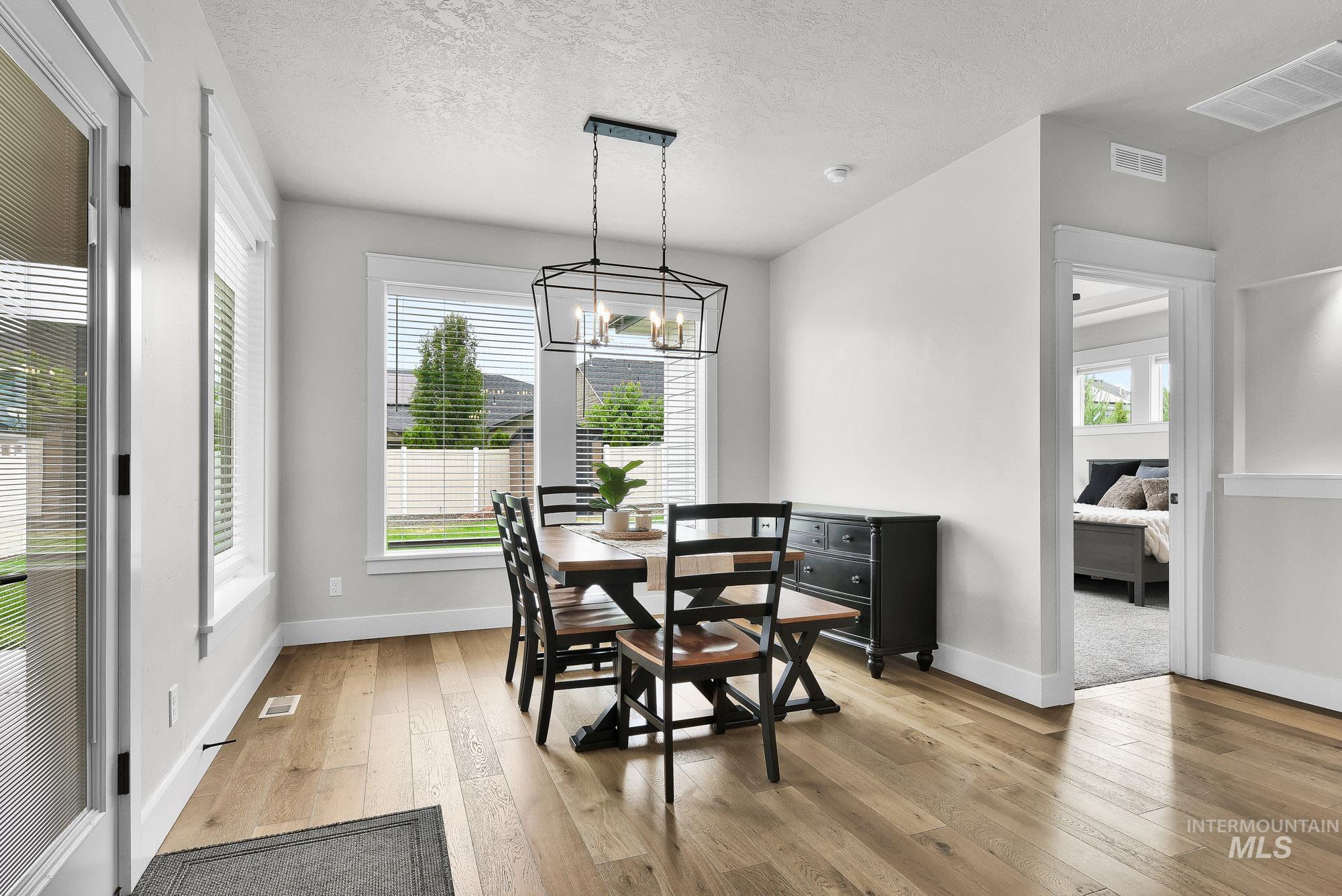 5676 East Zaffre Ridge Street Boise, ID 83716 - Photo 18 of 50 Dining space with wood-finish flooring, multiple windows, a modern geometric chandelier, and white trim