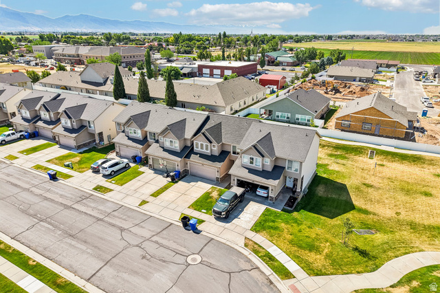 3215 West 450 North West Point, UT 84015 - Photo 35 of 40 Aerial perspective showcasing a residential street with multiple properties featuring attached garages, concrete driveways, and manicured front lawns