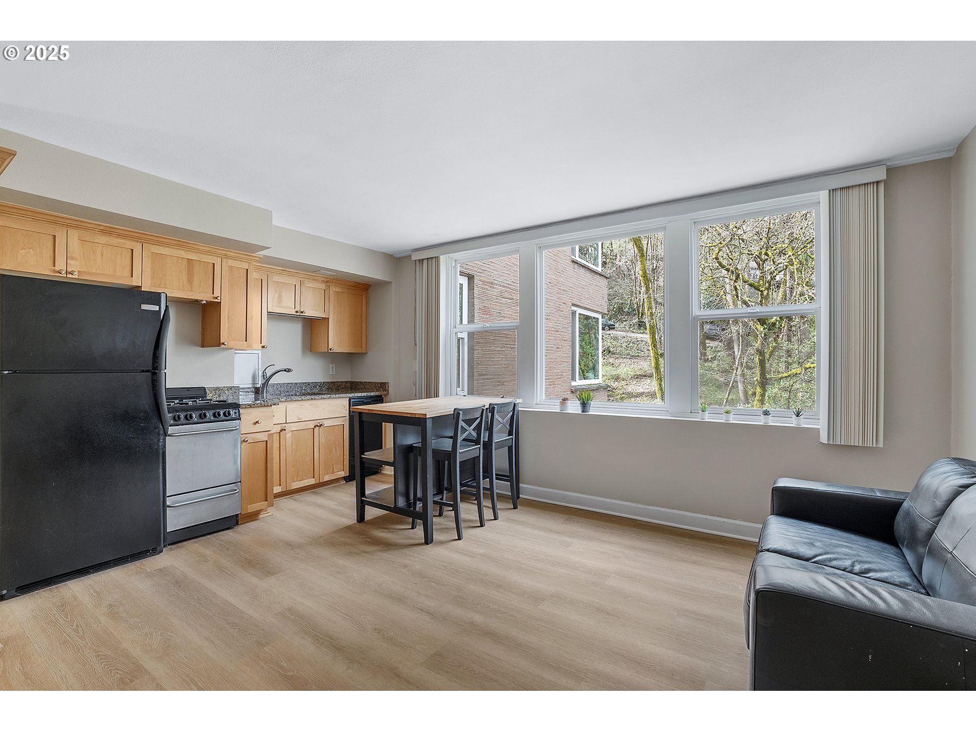 1205 Southwest Cardinell Drive, Unit 704 Portland, OR 97201 - Photo 7 of 23 a open kitchen with stainless steel appliances granite countertop a refrigerator a stove a sink dishwasher a dining table and chairs with wooden floor