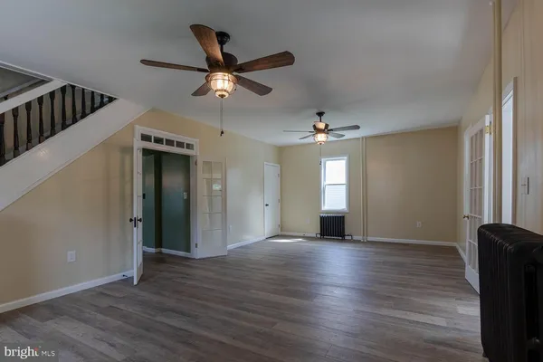 an empty room with wooden floor fan and windows