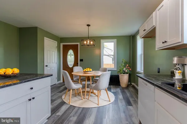a dining room with wooden floor a chandelier a wooden table and chairs