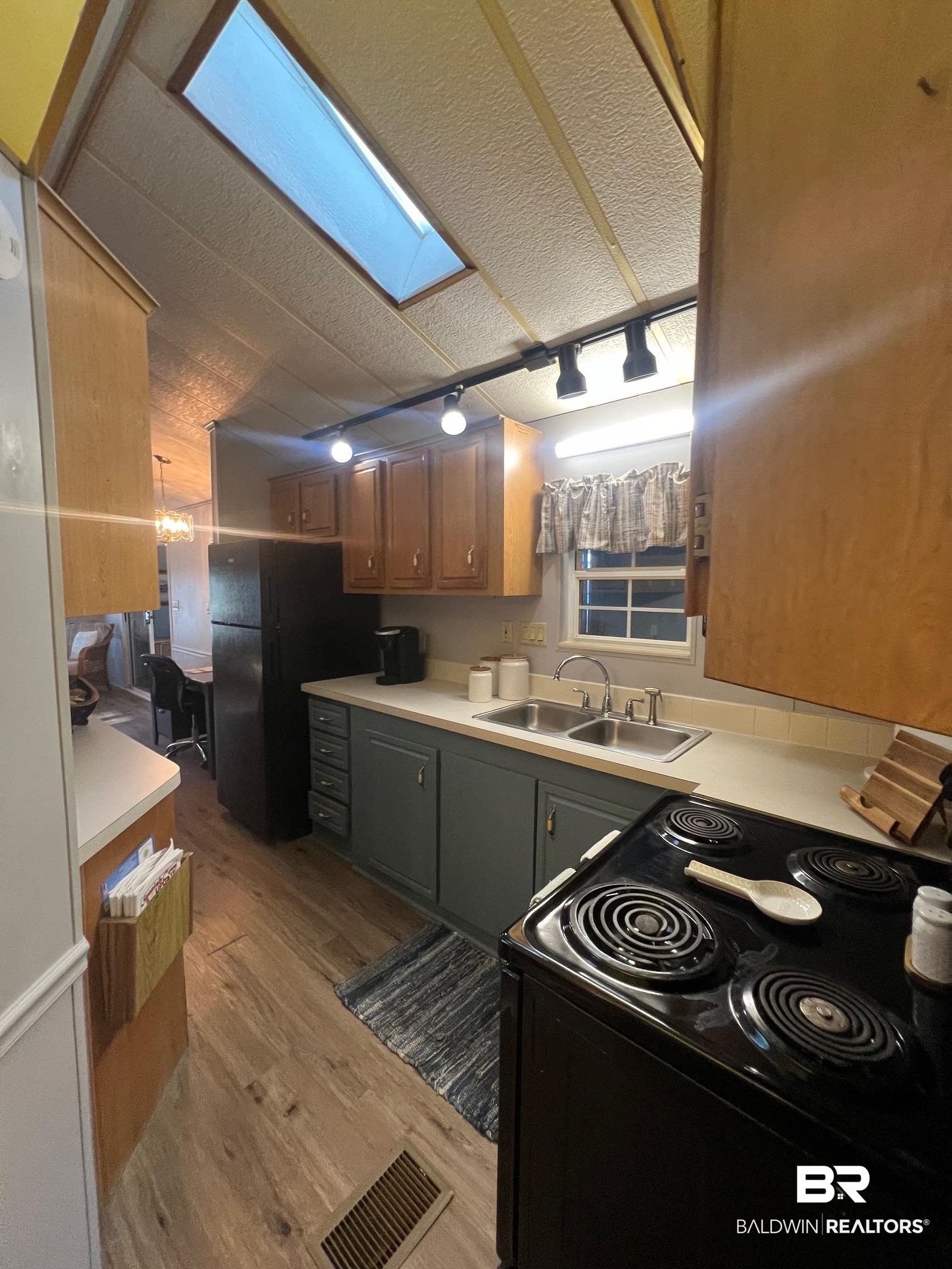 698 Escambia Loop Lillian, AL 36549 - Photo 9 of 16 Kitchen featuring a textured ceiling, black appliances, light hardwood / wood-style flooring, a skylight, and sink