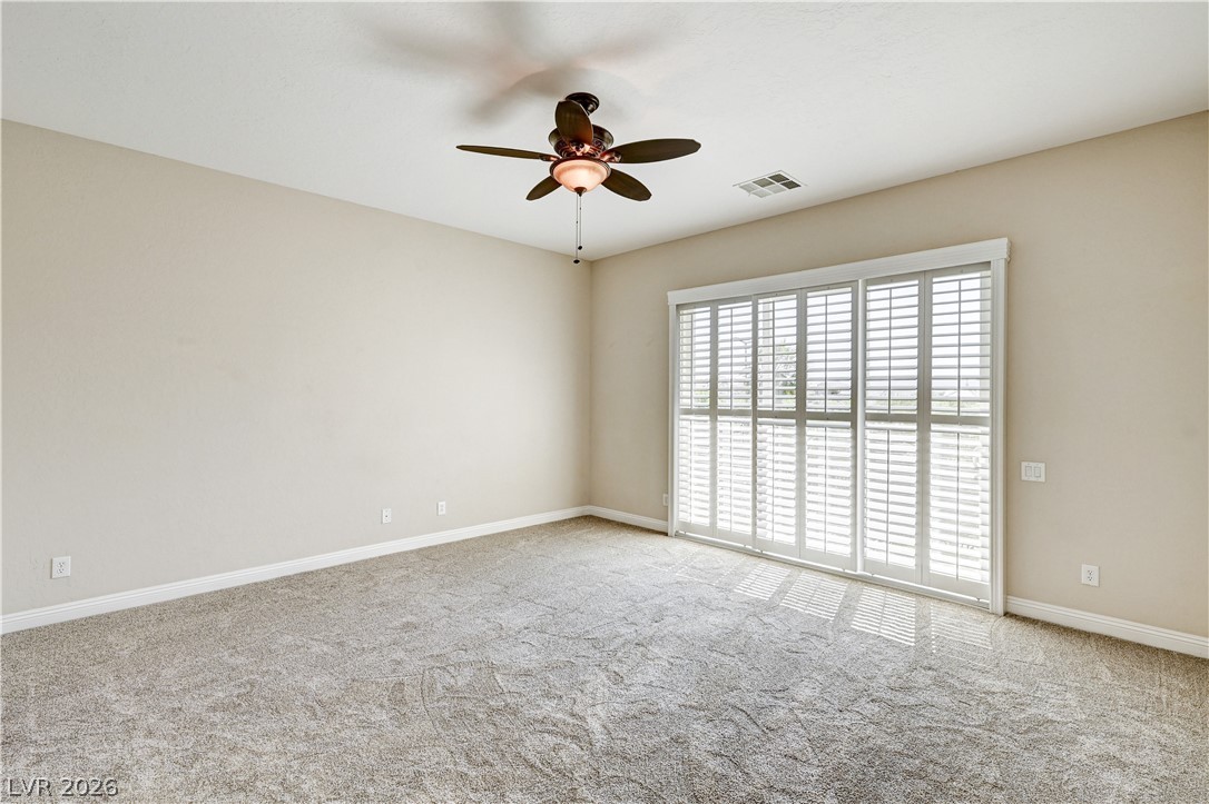2793 Rosenhearty Drive Henderson, NV 89044 - Photo 37 of 77 A well-proportioned bedroom features carpeted floors and bright sliding glass doors.