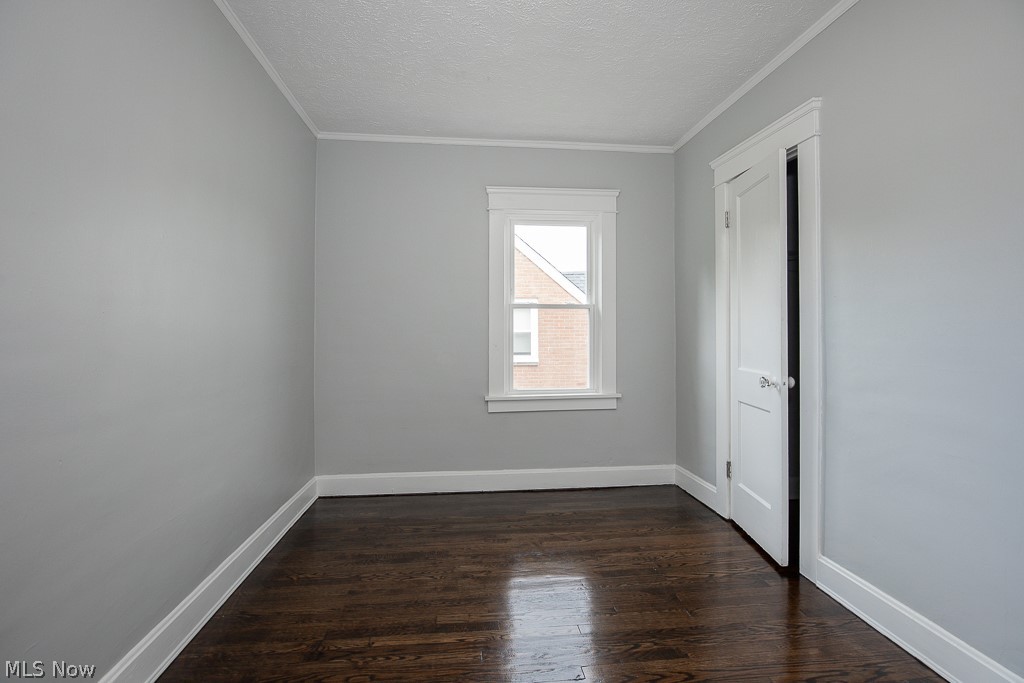 13131 Cedar Road Cleveland, OH 44118 - Photo 18 of 23 Empty room with ornamental molding, dark hardwood / wood-style floors, and a textured ceiling