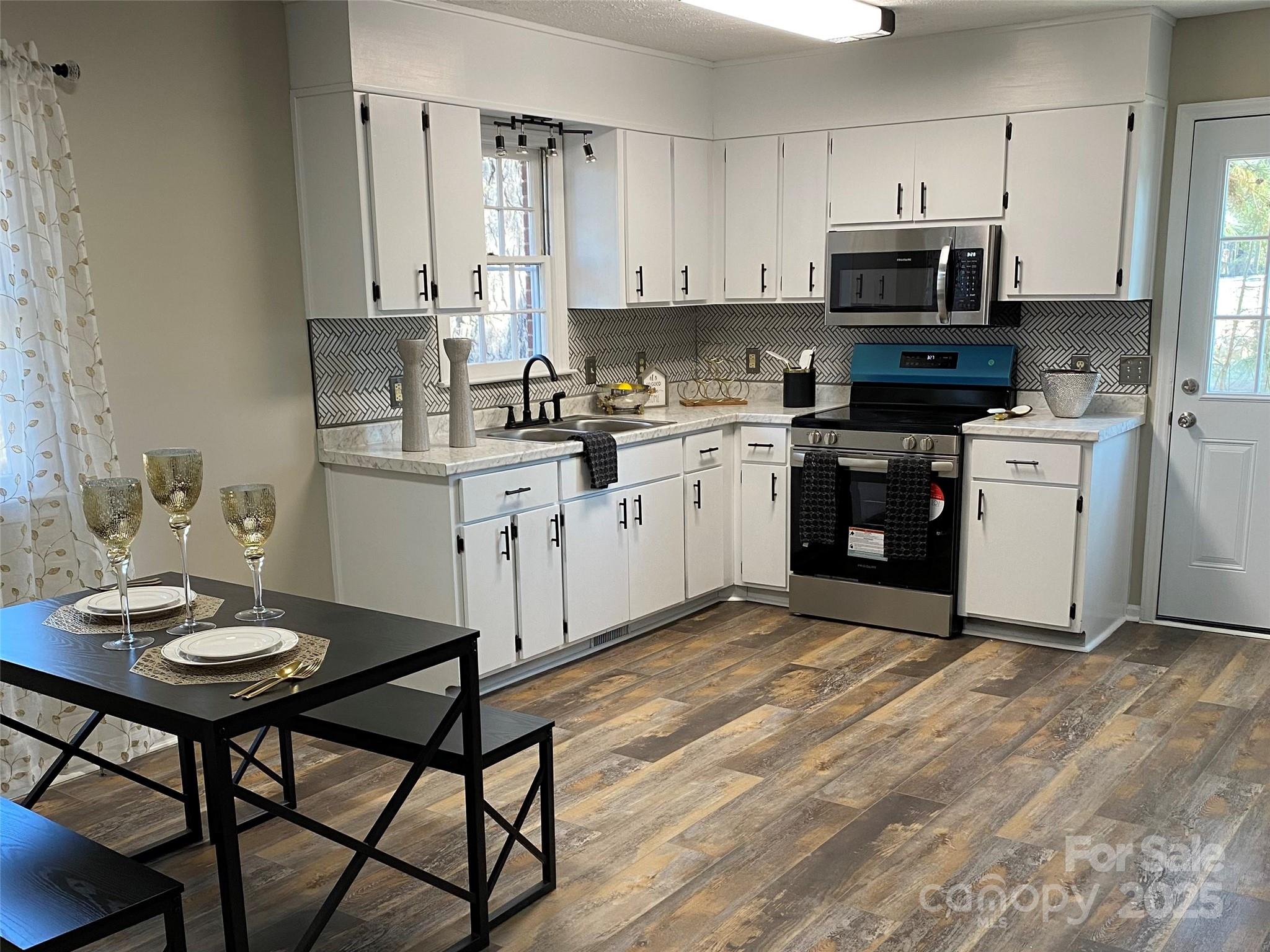 802 Marshall Street Cheraw, SC 29520 - Photo 6 of 16 a kitchen with stainless steel appliances granite countertop a stove a sink dishwasher a microwave oven with a dining table and chairs