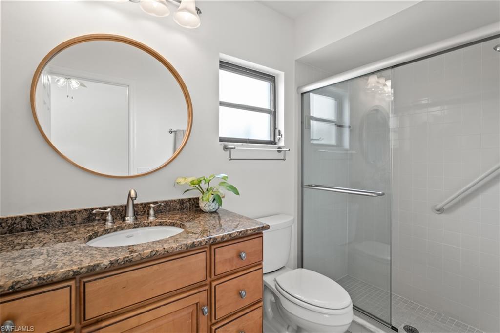 1348 Monarch Circle Naples, FL 34116 - Photo 17 of 33 a bathroom with a granite countertop toilet a sink and a mirror