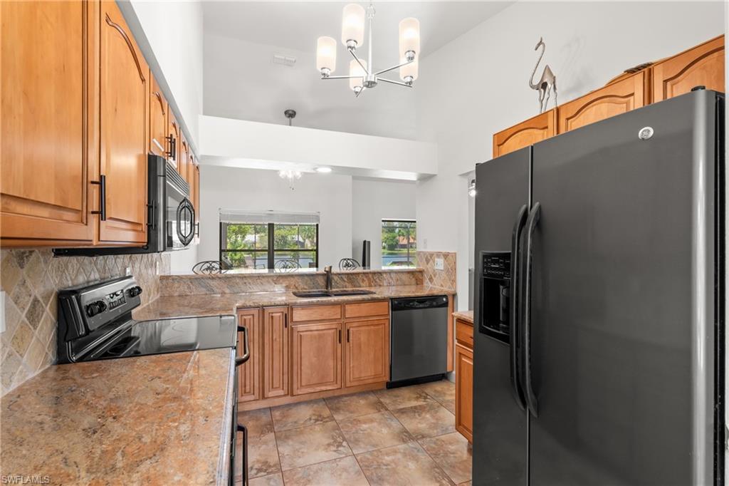 1348 Monarch Circle Naples, FL 34116 - Photo 8 of 33 a kitchen with stainless steel appliances granite countertop a refrigerator a sink dishwasher with a dining table and chairs