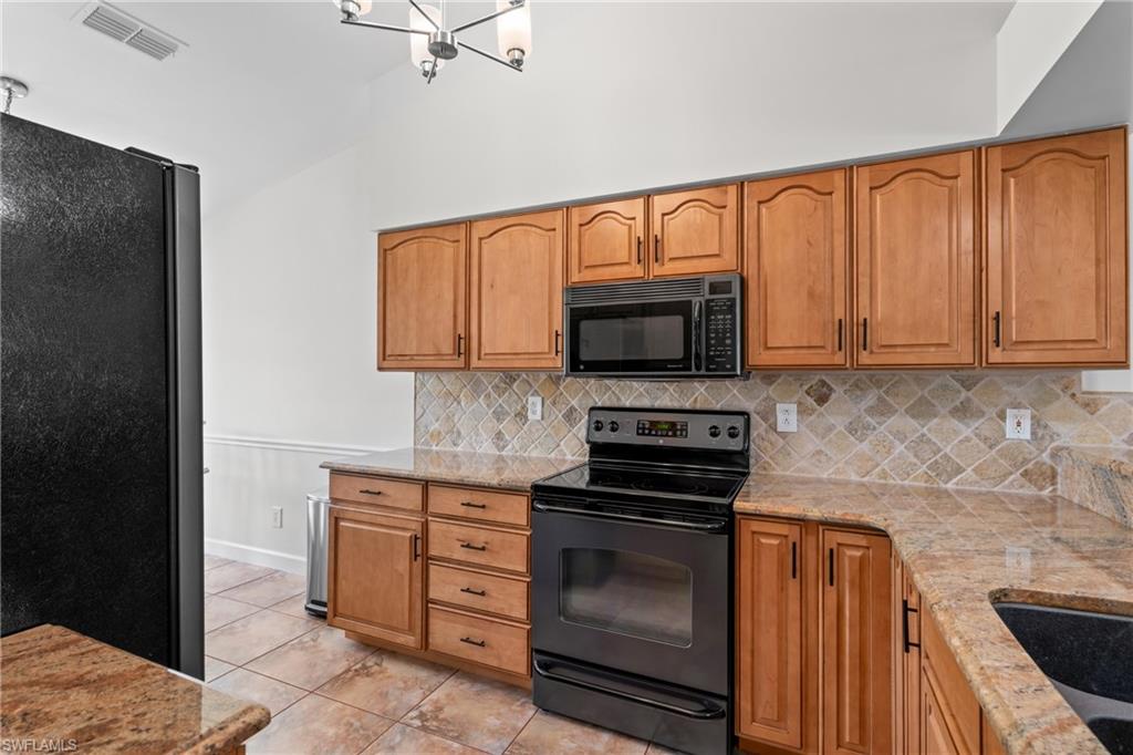 1348 Monarch Circle Naples, FL 34116 - Photo 10 of 33 a kitchen with stainless steel appliances granite countertop a stove microwave and refrigerator