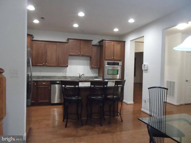 13113 Winding Trail Road Laurel, MD 20707 - Photo 16 of 47 a kitchen with stainless steel appliances granite countertop a table chairs and a refrigerator