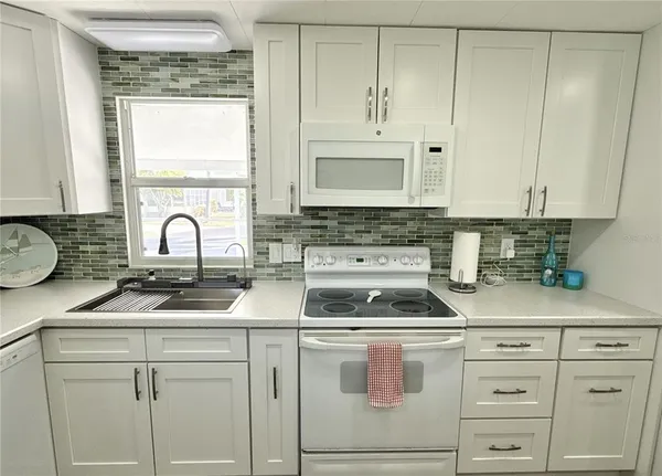 a kitchen with white cabinets sink and window
