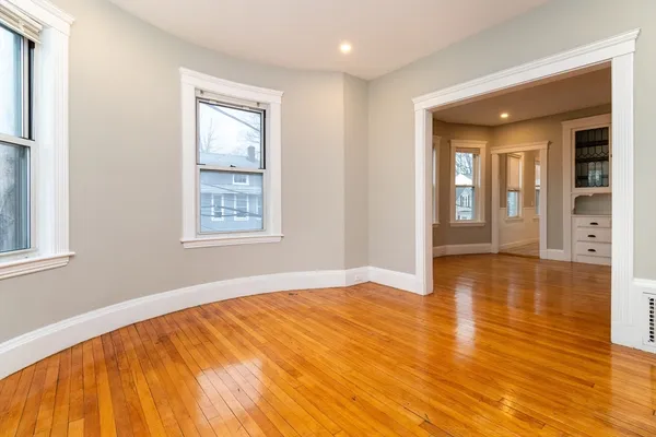 a view of an empty room with wooden floor and a window