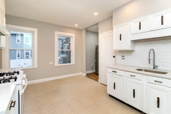 a kitchen with white cabinets and sink