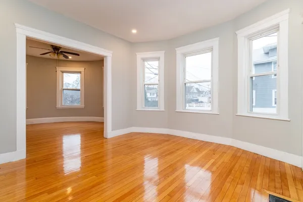a view of an empty room with wooden floor and a window