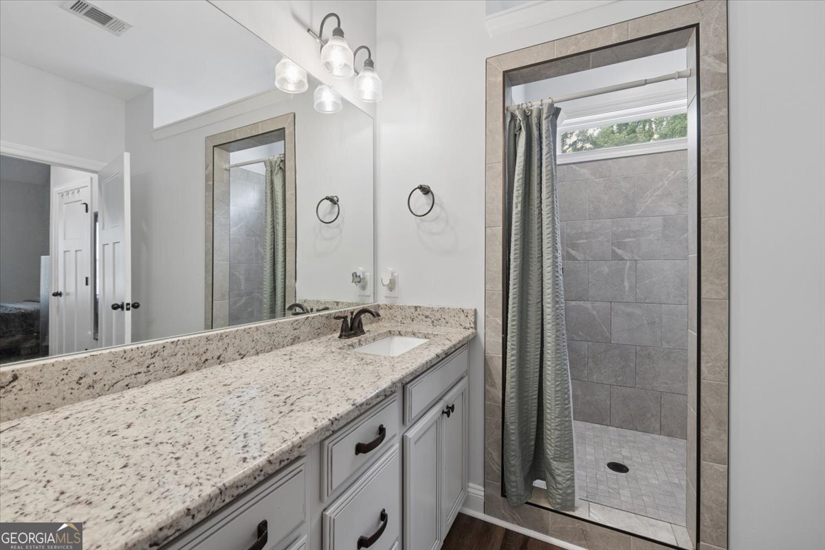 683 Teagle Road Forsyth, GA 31029 - Photo 27 of 50 a bathroom with a granite countertop sink a mirror and shower