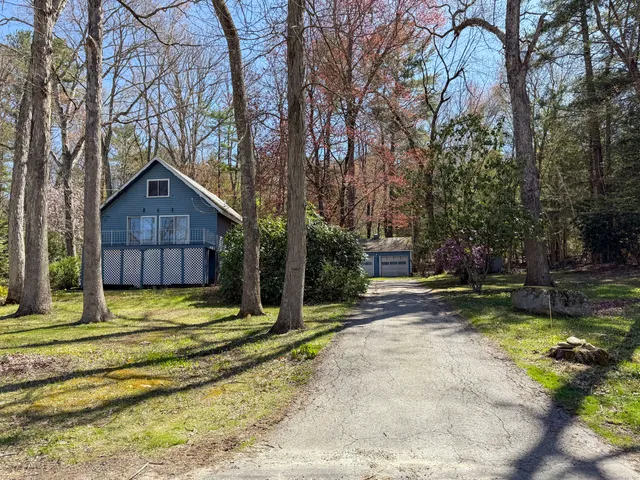a view of a house with a yard and large trees