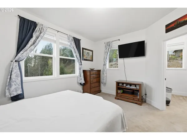 a bedroom with a bed a television and a large window