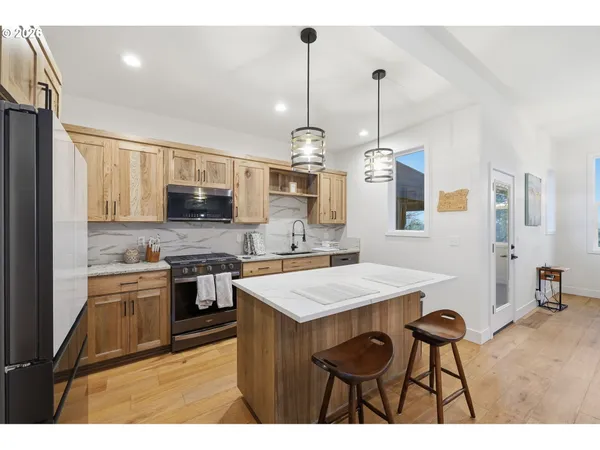 a kitchen with stainless steel appliances kitchen island granite countertop a stove a sink dishwasher and a refrigerator with wooden cabinets