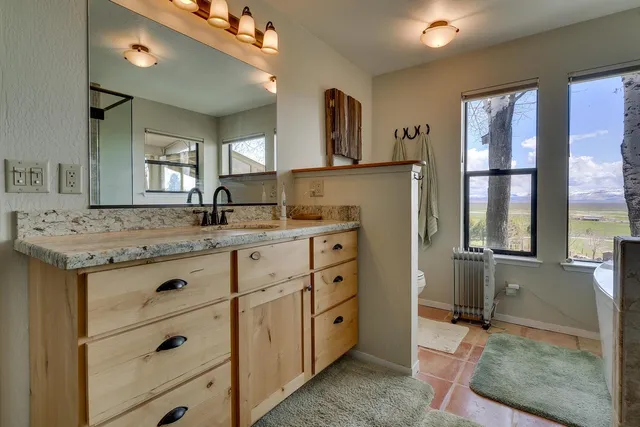a bathroom with a granite countertop sink mirror and window