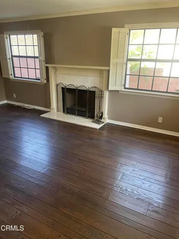 an empty room with wooden floor fan and windows