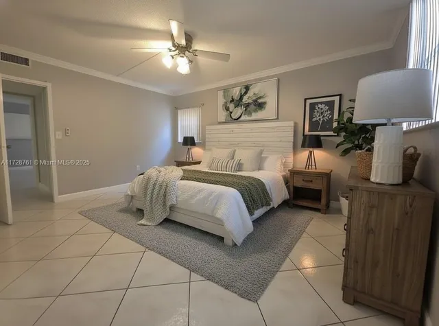 a spacious bedroom with a bed and lamp on the dresser