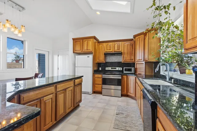 a kitchen with stainless steel appliances granite countertop a stove a sink and a refrigerator