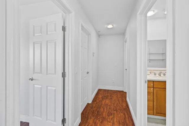 a view of a hallway with wooden floor and a bathroom