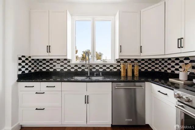 a kitchen with white cabinets and sink