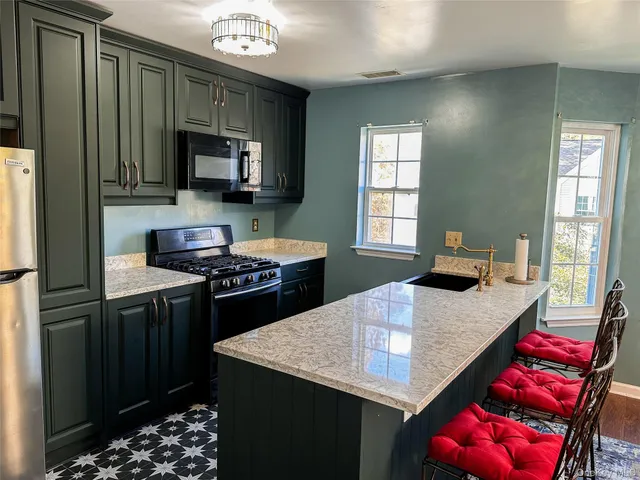 a kitchen with stainless steel appliances kitchen island granite countertop a stove refrigerator and microwave