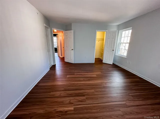 a view of an empty room with wooden floor and window