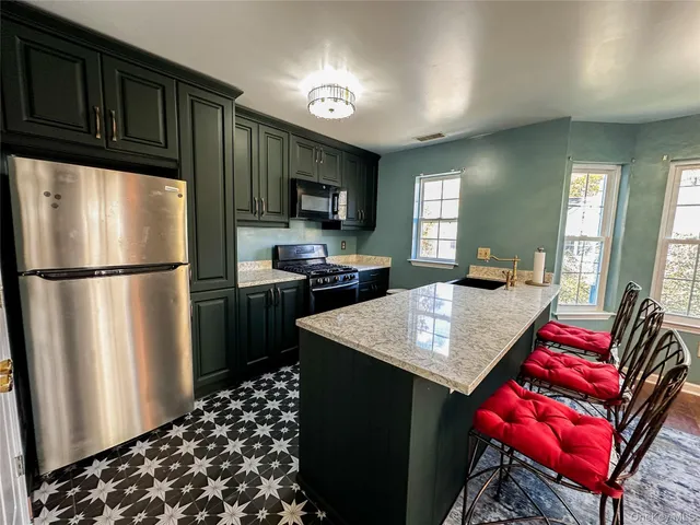 a kitchen with stainless steel appliances granite countertop a refrigerator a stove a sink dishwasher a dining table and chairs with wooden floor