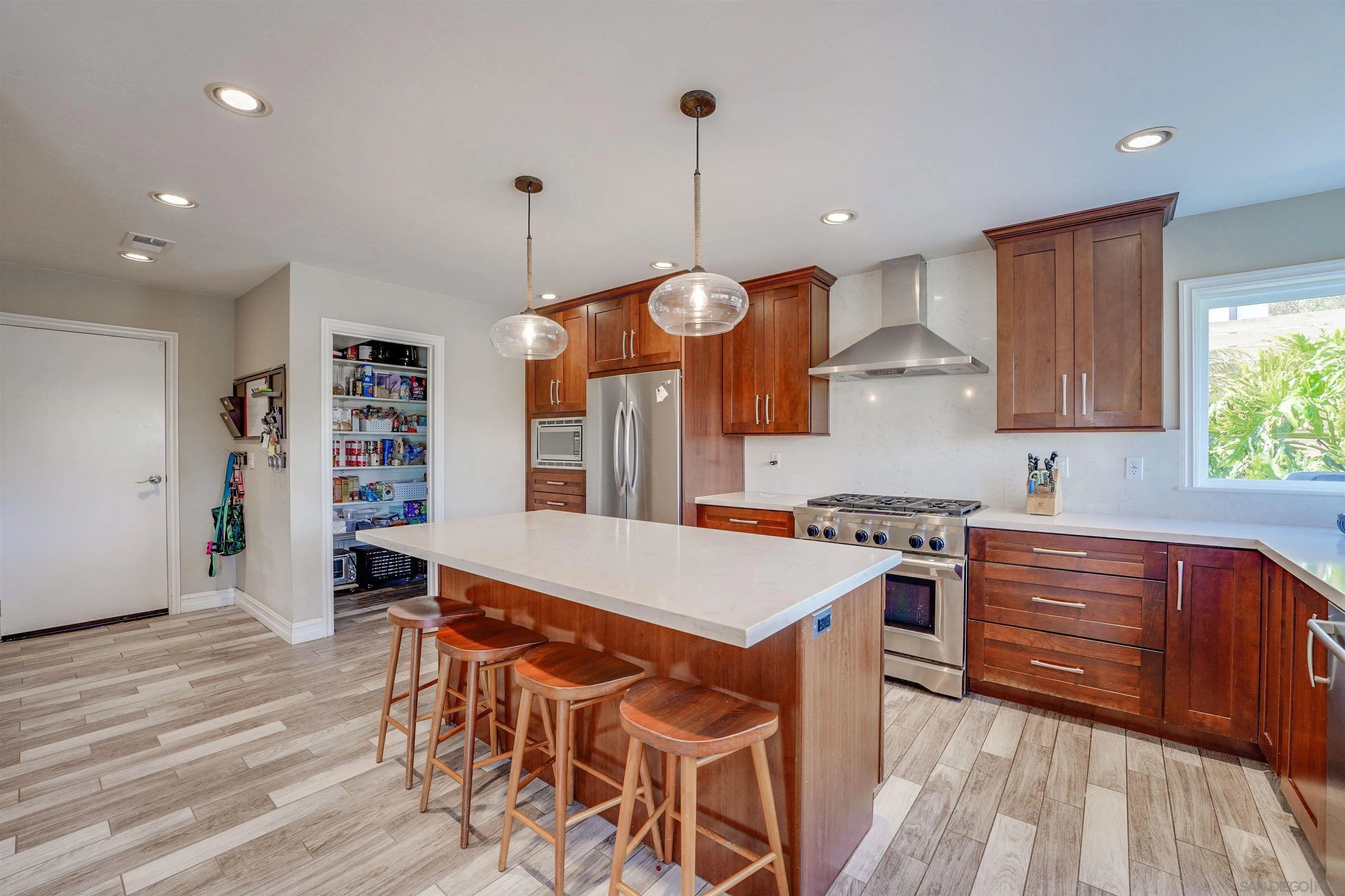 1647 Hawk View Drive Encinitas, CA 92024 - Photo 15 of 73 a large kitchen with stainless steel appliances granite countertop a stove a sink dishwasher and a dining table with wooden floor