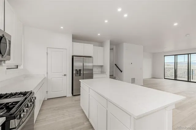 a large kitchen with stainless steel appliances a refrigerator and a stove top oven