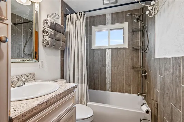 a bathroom with a granite countertop sink a toilet and shower