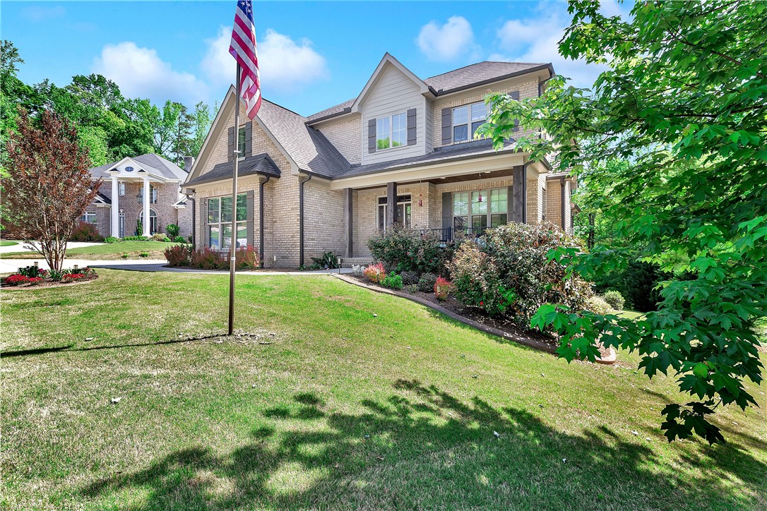 This charming home offers classic brick construction and a welcoming front porch set amidst lush greenery.