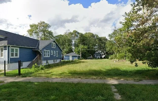 a view of a big house with a big yard and large trees
