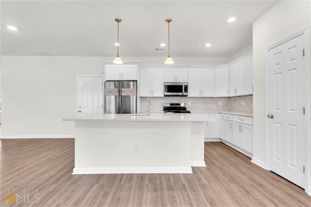 860 North Bethany Road McDonough, GA 30252 - Photo 26 of 57 a large white kitchen with wooden floor and stainless steel appliances