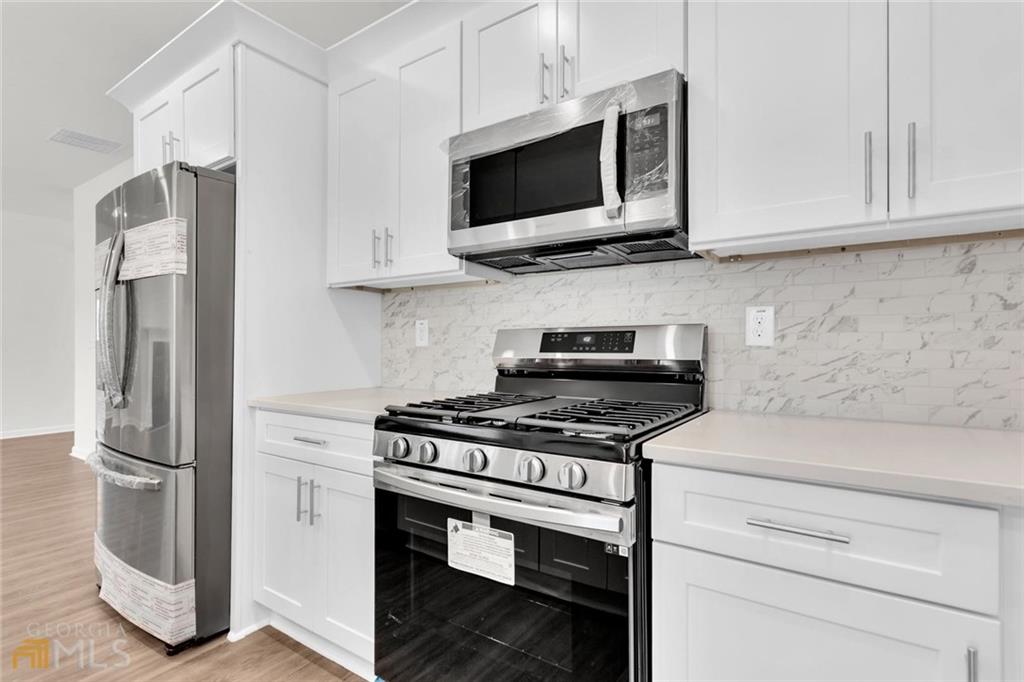 860 North Bethany Road McDonough, GA 30252 - Photo 30 of 57 a kitchen with stainless steel appliances white cabinets and a stove top oven