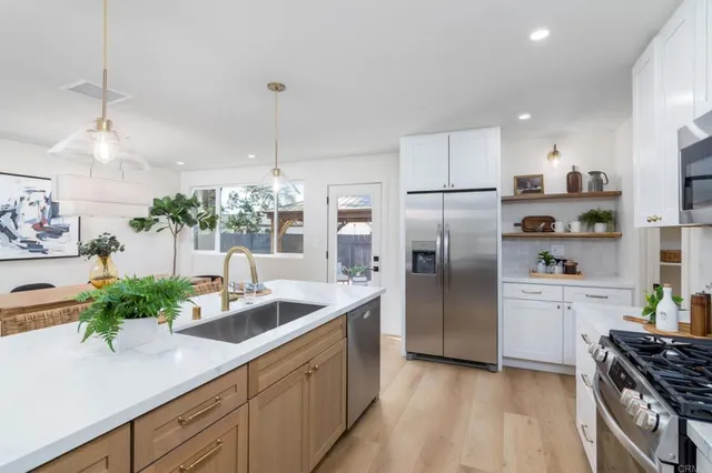 a kitchen with stainless steel appliances granite countertop a refrigerator a oven a sink a stove and white cabinets