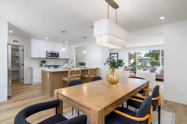 a kitchen with stainless steel appliances granite countertop a stove a refrigerator a kitchen island a sink a dining table and chairs