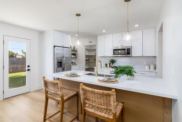 a kitchen with stainless steel appliances kitchen island granite countertop a refrigerator a stove a oven a sink a dining table and chairs with wooden floor